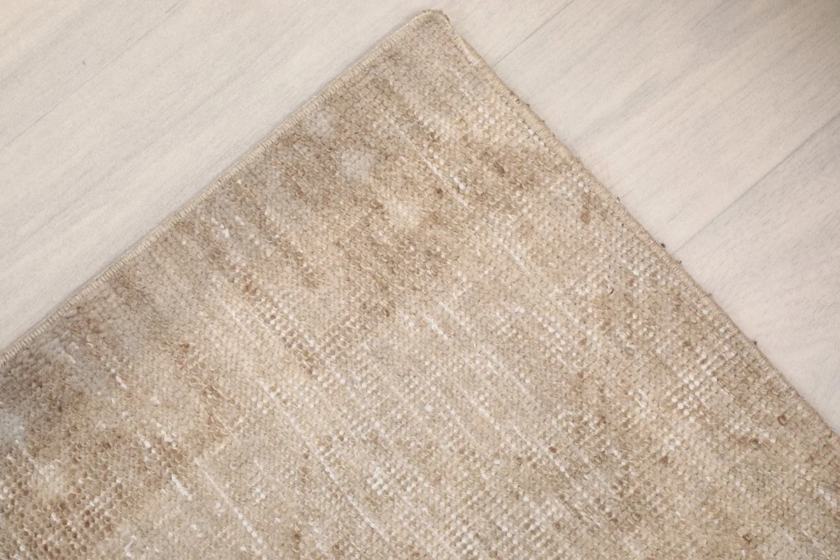 Corner detail of the rug, emphasizing the subtle border and overall distressed appearance