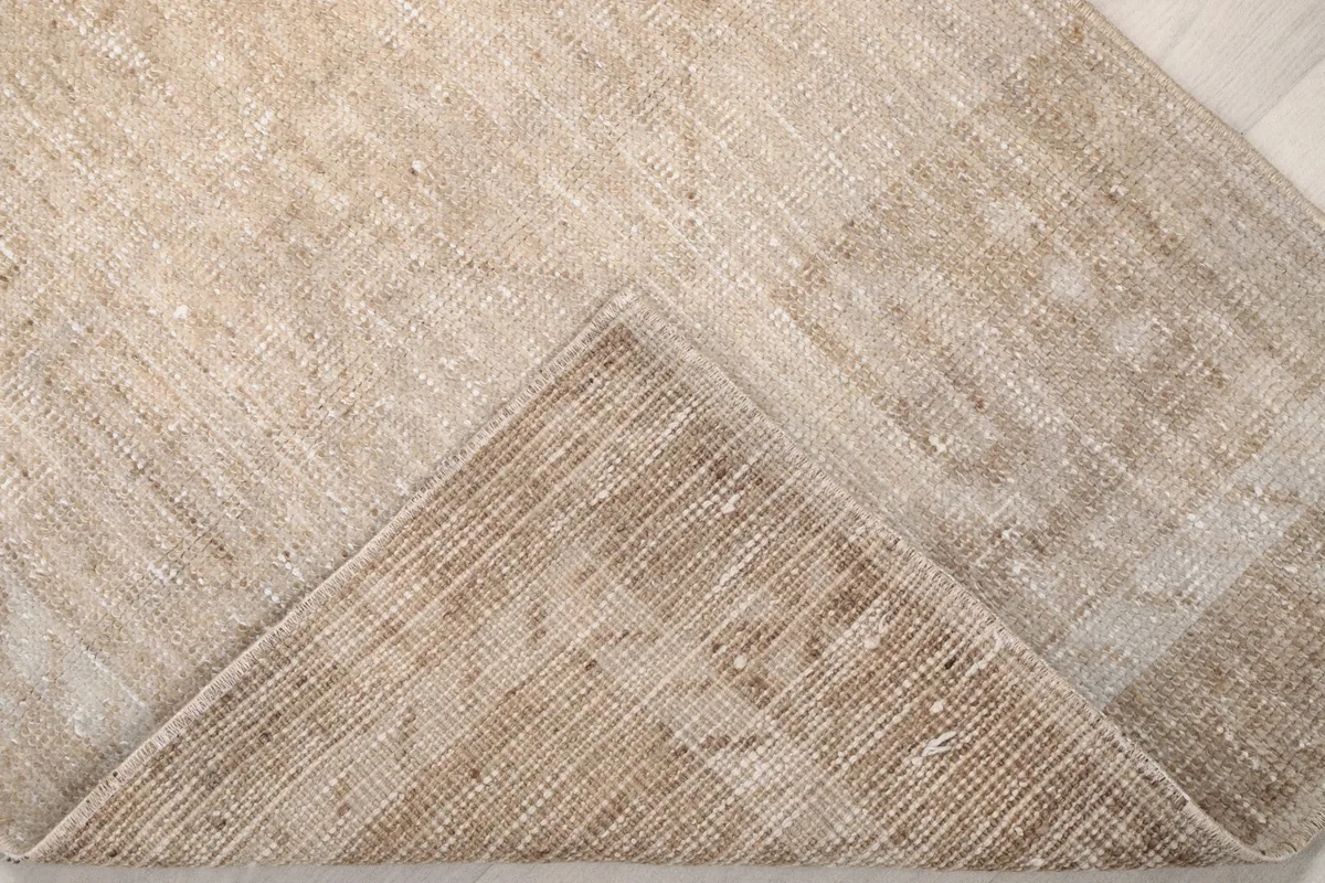 View of the back of the rug, folded to show the cotton foundation and knotting