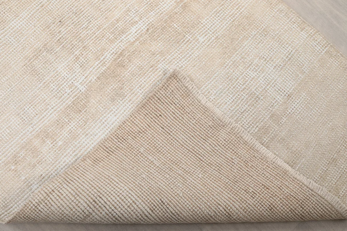 Corner of the rug folded back to reveal the cotton foundation and hand-knotted construction.