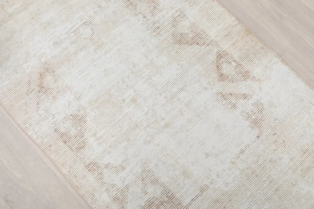 Close-up of the faded beige geometric motifs on the cream field of the hand-knotted runner