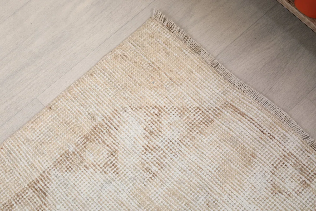 Corner detail of the vintage runner rug, highlighting the worn edges and low pile