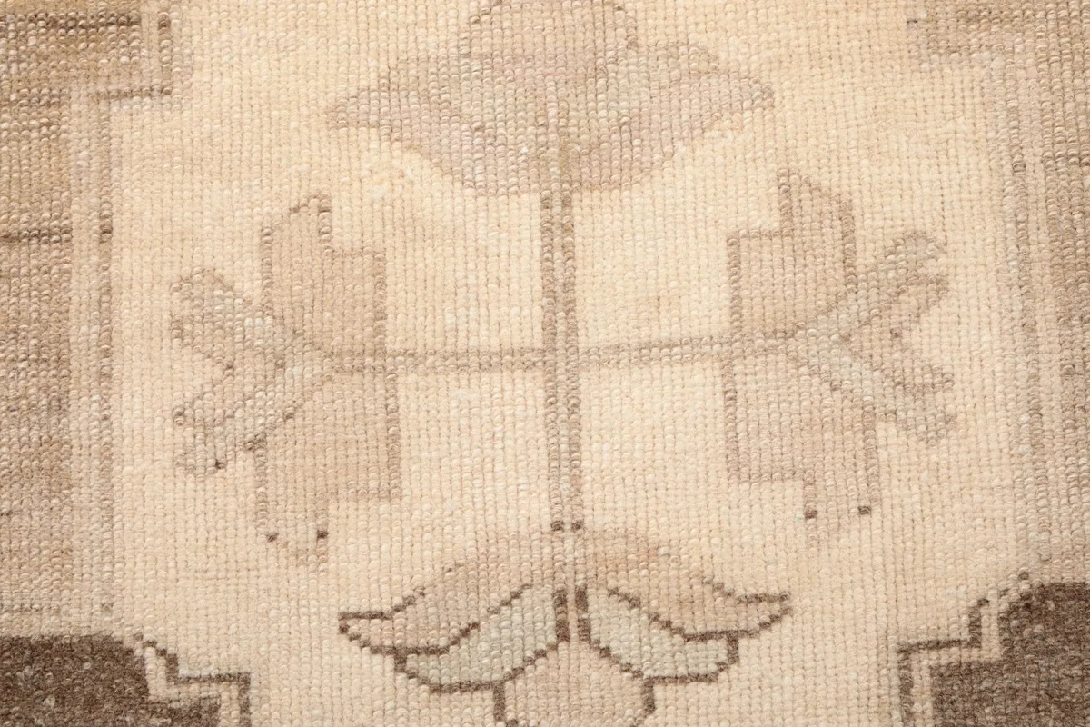 Detailed view of the intricate ivory and beige motifs within a geometric medallion