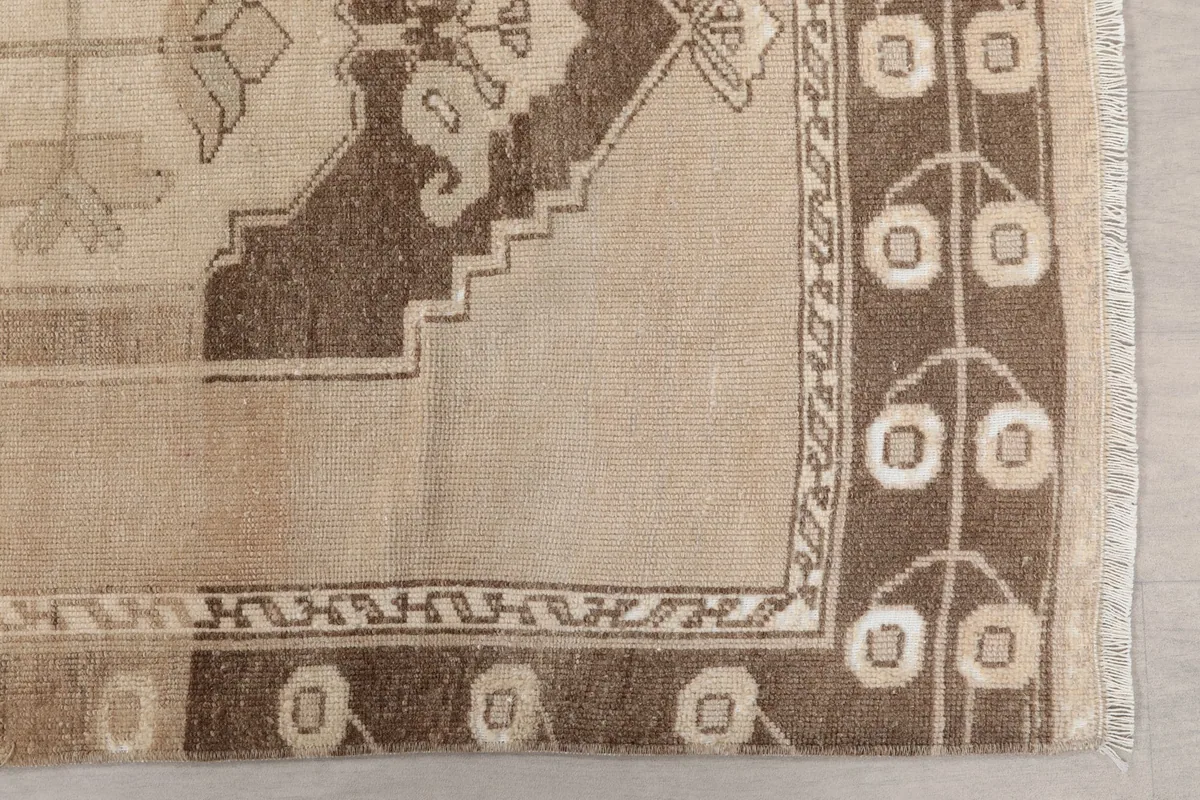 Detailed view of the brown border with ivory geometric patterns and the beige field
