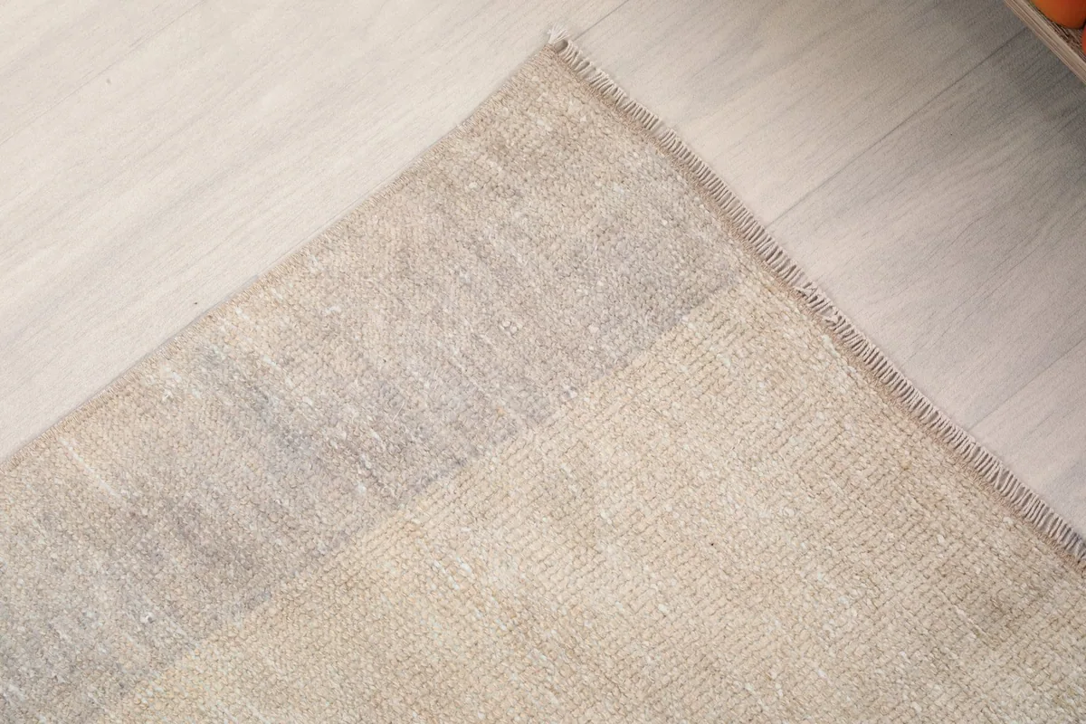 Close-up of the rug's edge and subtle border design, showcasing the hand-finished quality.