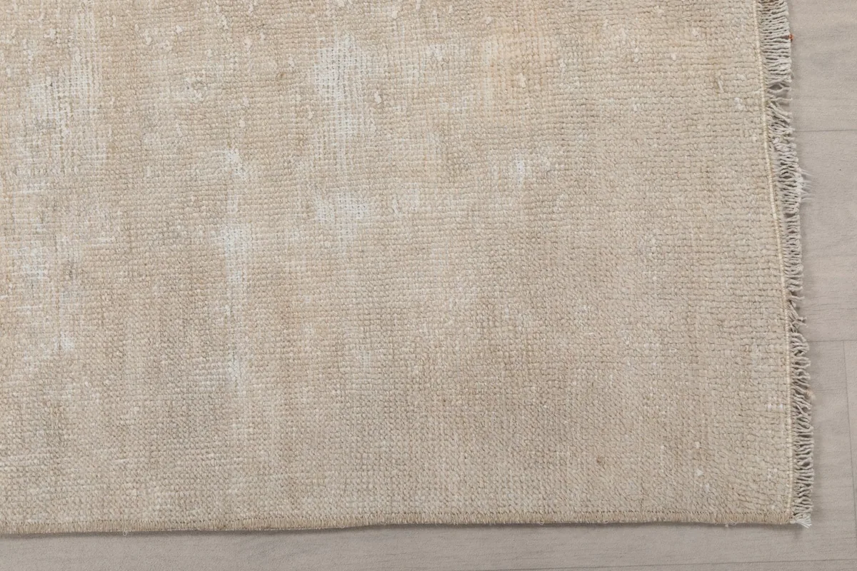 Detailed view of the distressed beige wool pile and subtle color variations