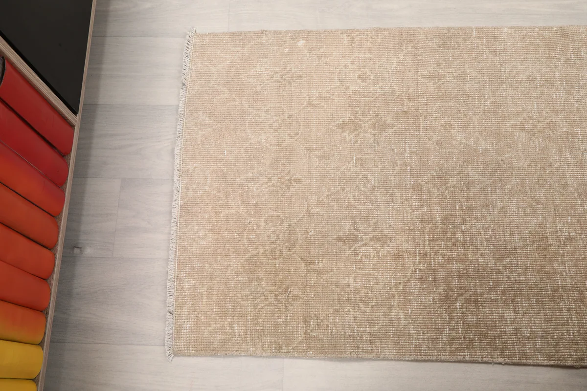 Faded Beige Geometric Anatolian Rug in a room, capturing its subtle pattern from an angle.