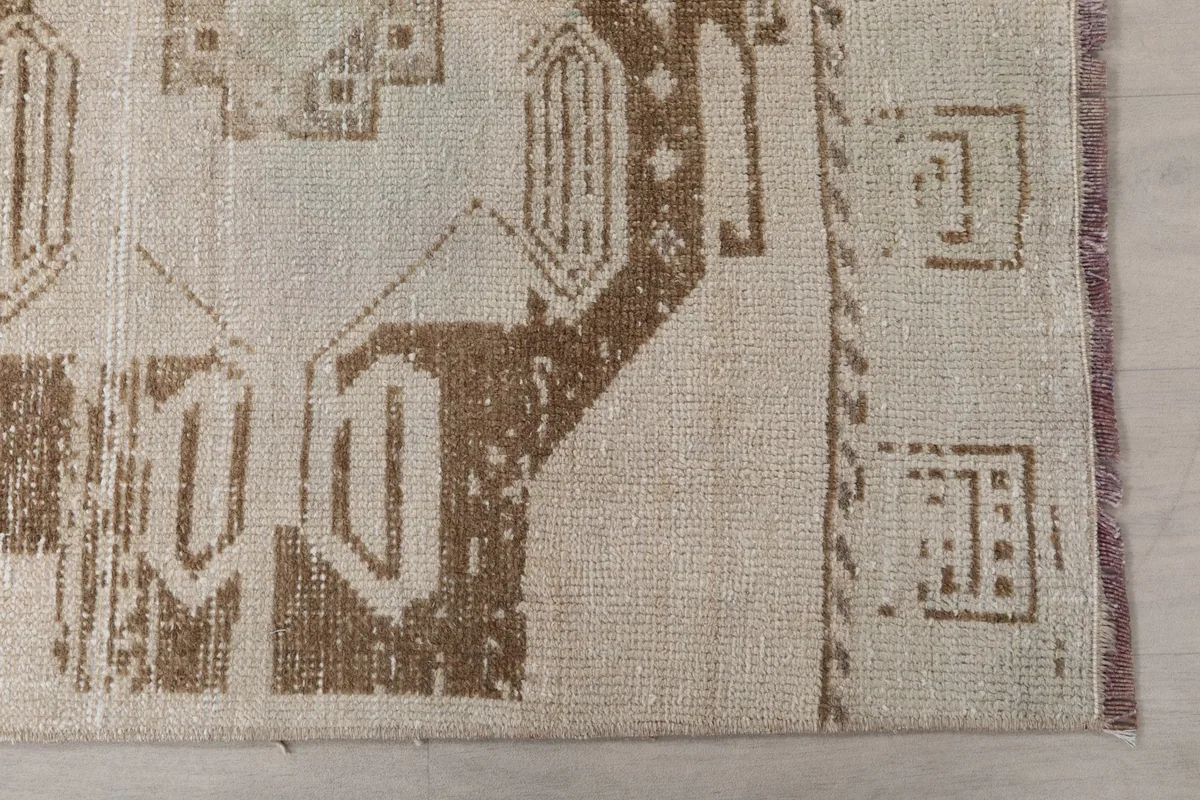 Detailed view of the brown geometric motifs and the cream field, showing slight wear.