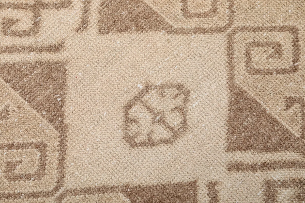 Macro detail of the wool pile and knotting texture within a brown geometric design