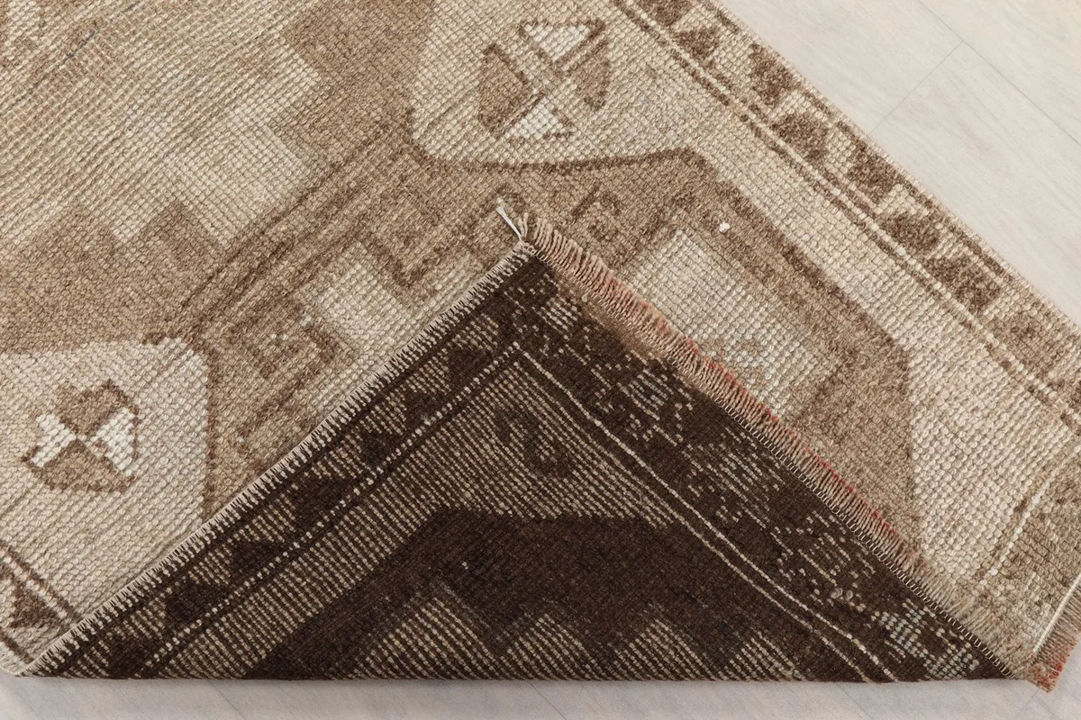 View of the underside of a corner of the rug, showing the cotton foundation and knotting