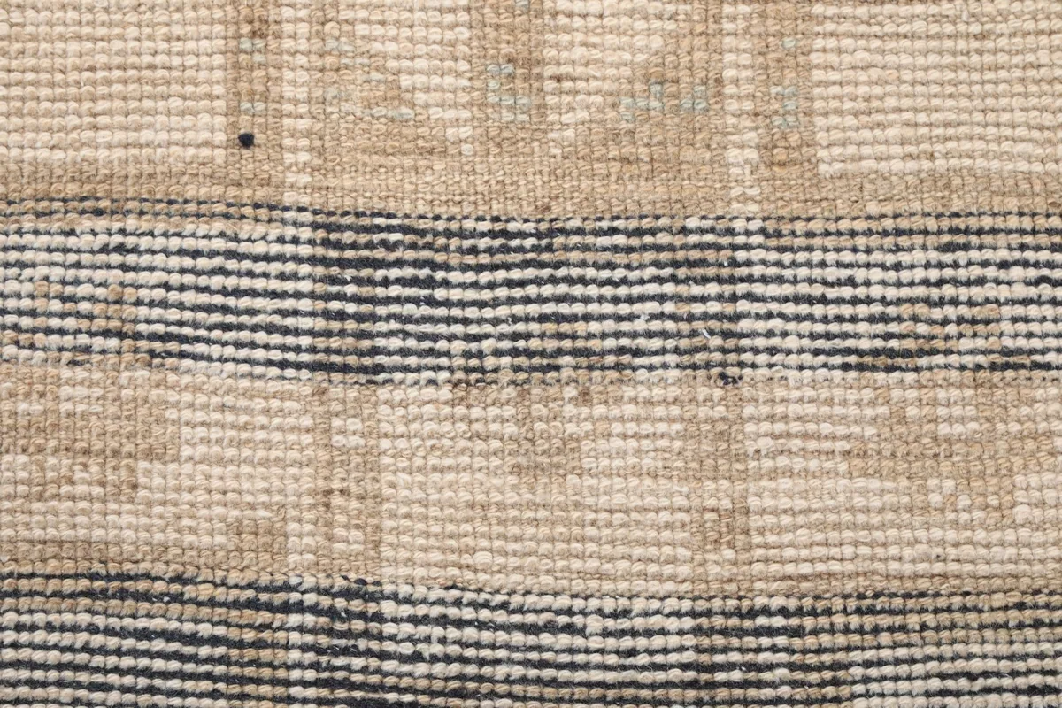 Texture of the hand-knotted wool pile, highlighting the blend of charcoal and beige threads