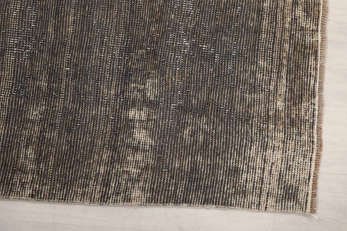 Detail view of the hand-knotted wool pile showing charcoal, gray, and beige threads