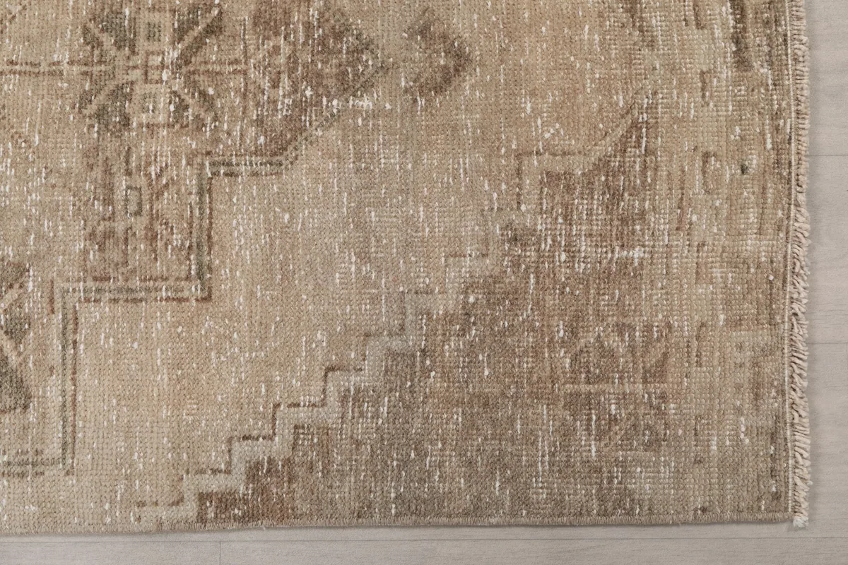 Detailed view of the rug's surface, showing the beige and brown colors with natural wear