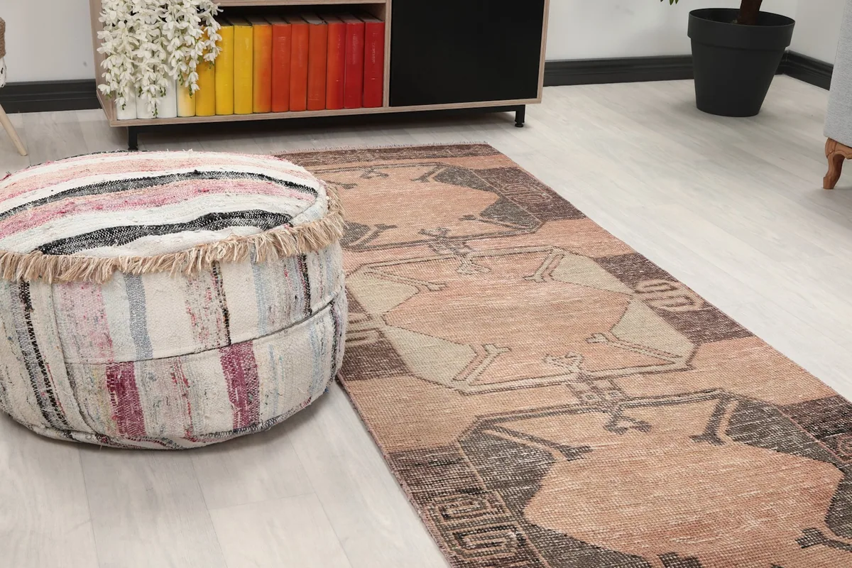 Close-up of the runner rug's pattern next to a striped ottoman in a room setting