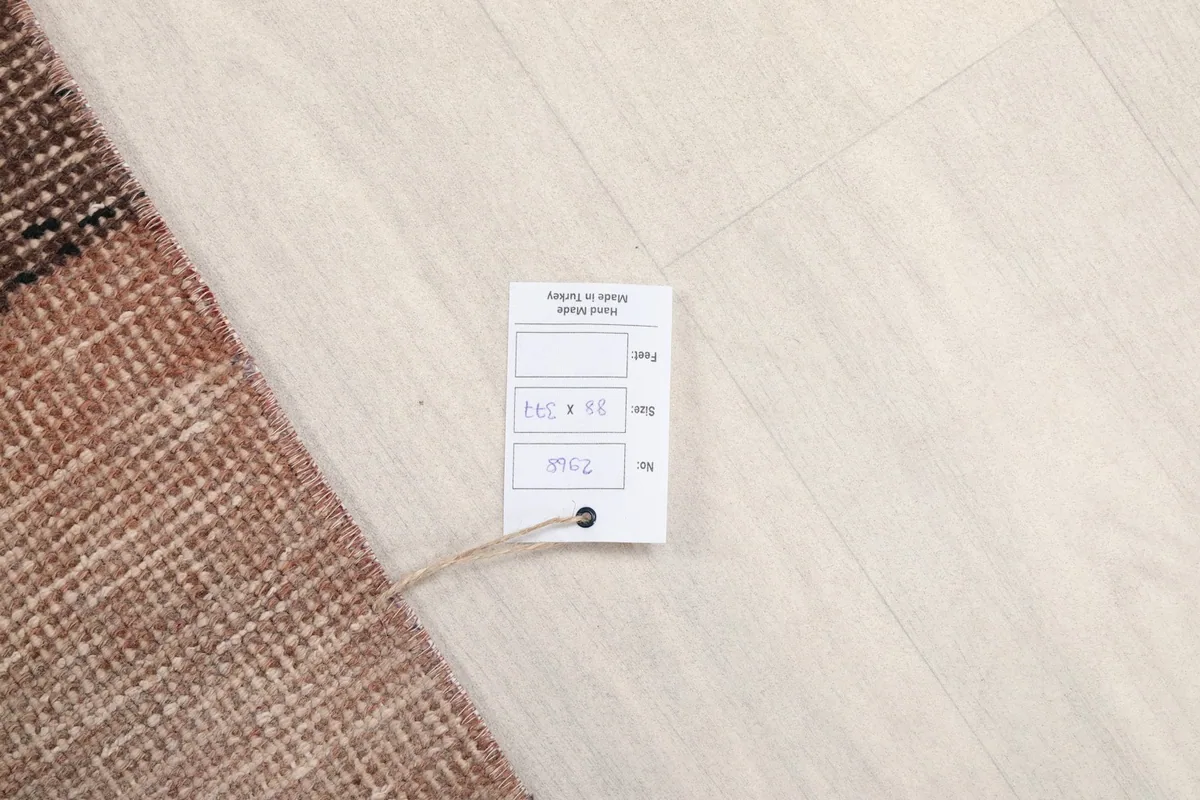 Hang tag displaying the rug's dimensions and origin, placed on the light floor
