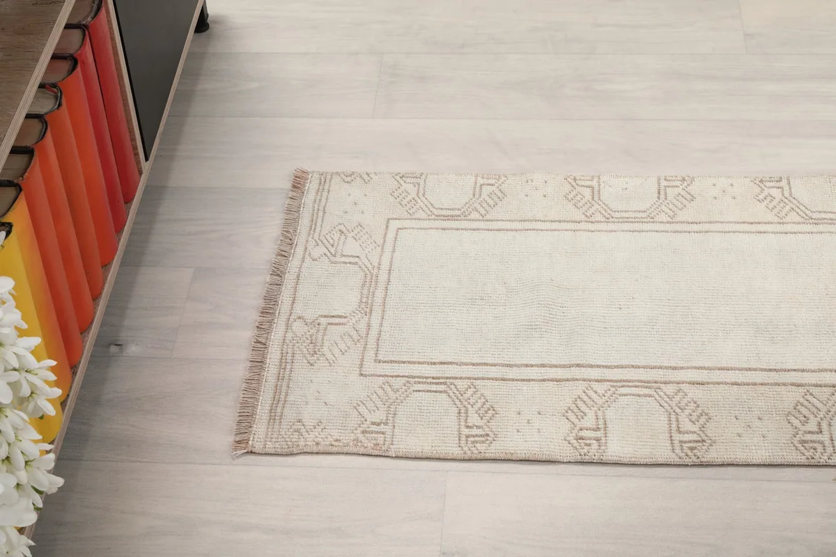 Angled shot of the runner rug, showcasing its length and the subtle variations in the beige border pattern.