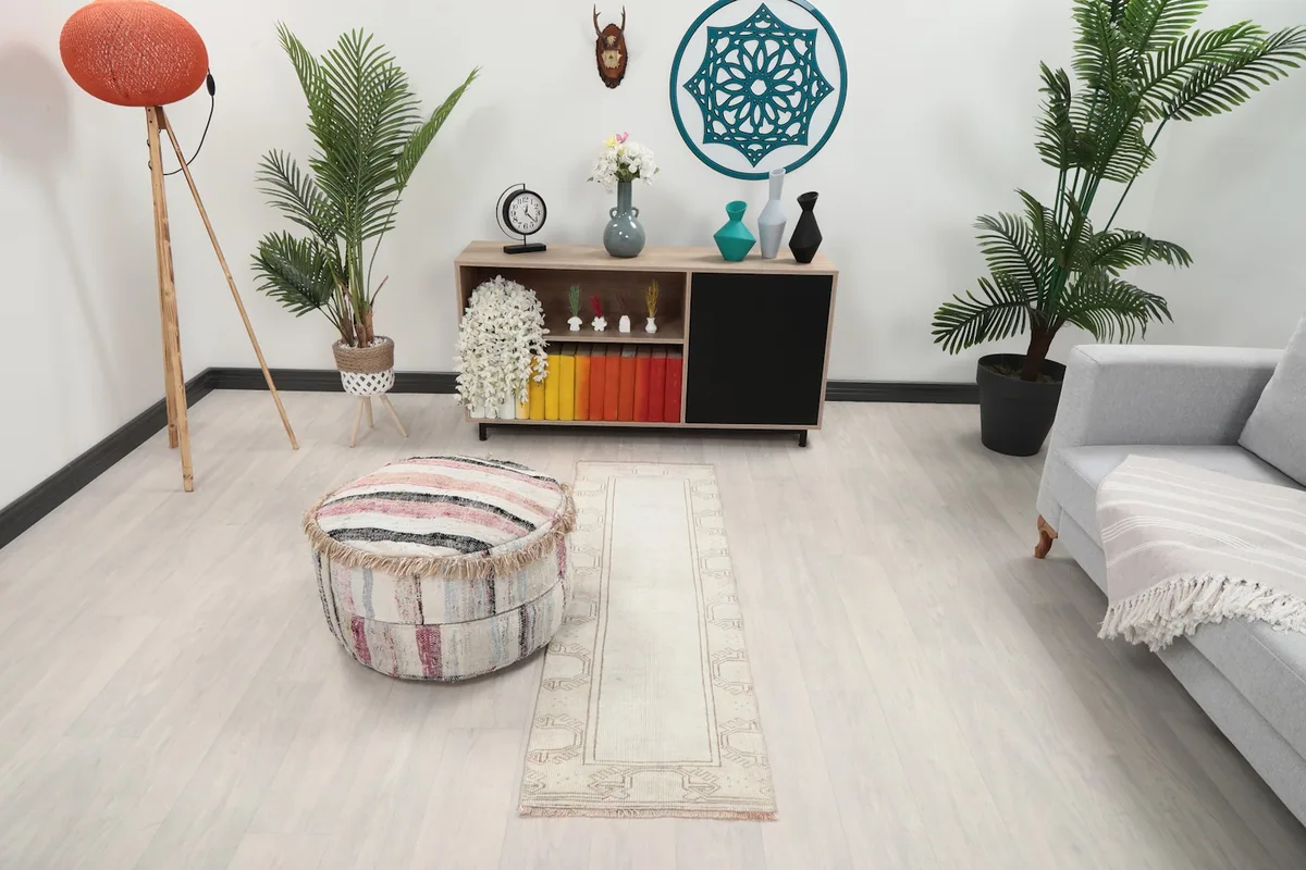 Vintage cream runner rug in a modern living space with a sofa and ottoman, showing its full length.
