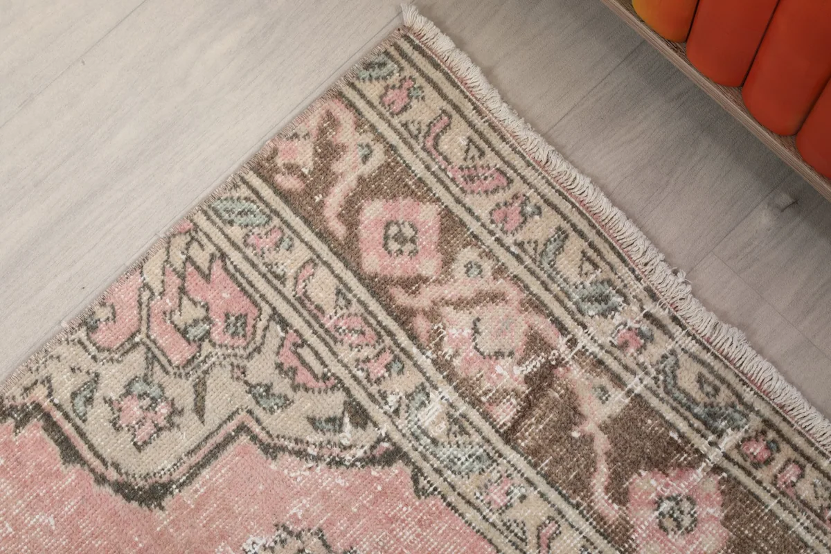 Corner detail of the rug's border pattern in brown and beige, with rose field visible