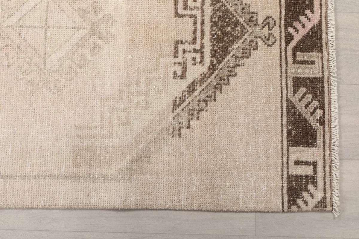 Detailed view of the brown geometric border and a section of the beige field pattern at one end.
