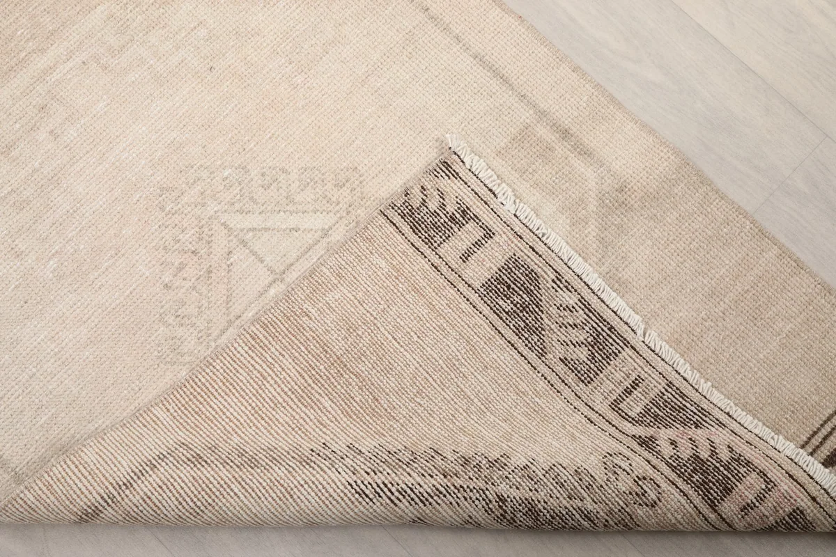 Corner of the rug folded to show the hand-knotted construction and cotton foundation on the reverse side.