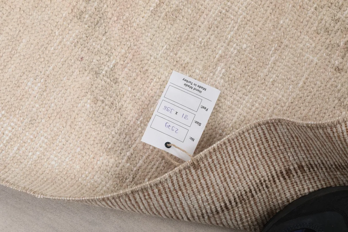 Close-up of the rug's back with a product tag, indicating its origin and dimensions.