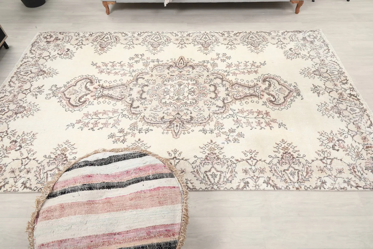 Full overhead view of the ivory rug with a decorative pouf