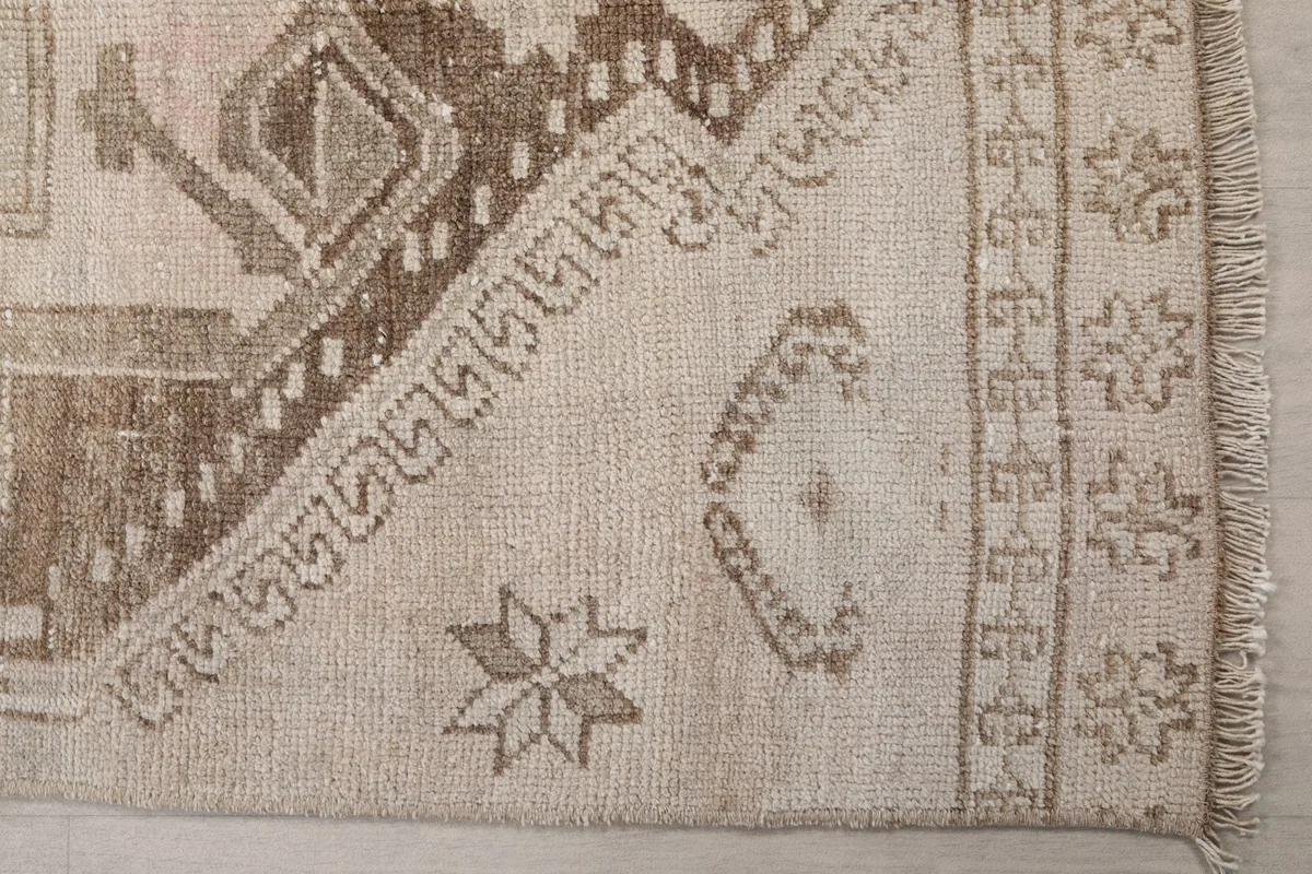 Detailed view of the hand-knotted wool pile and geometric patterns at one end of the rug