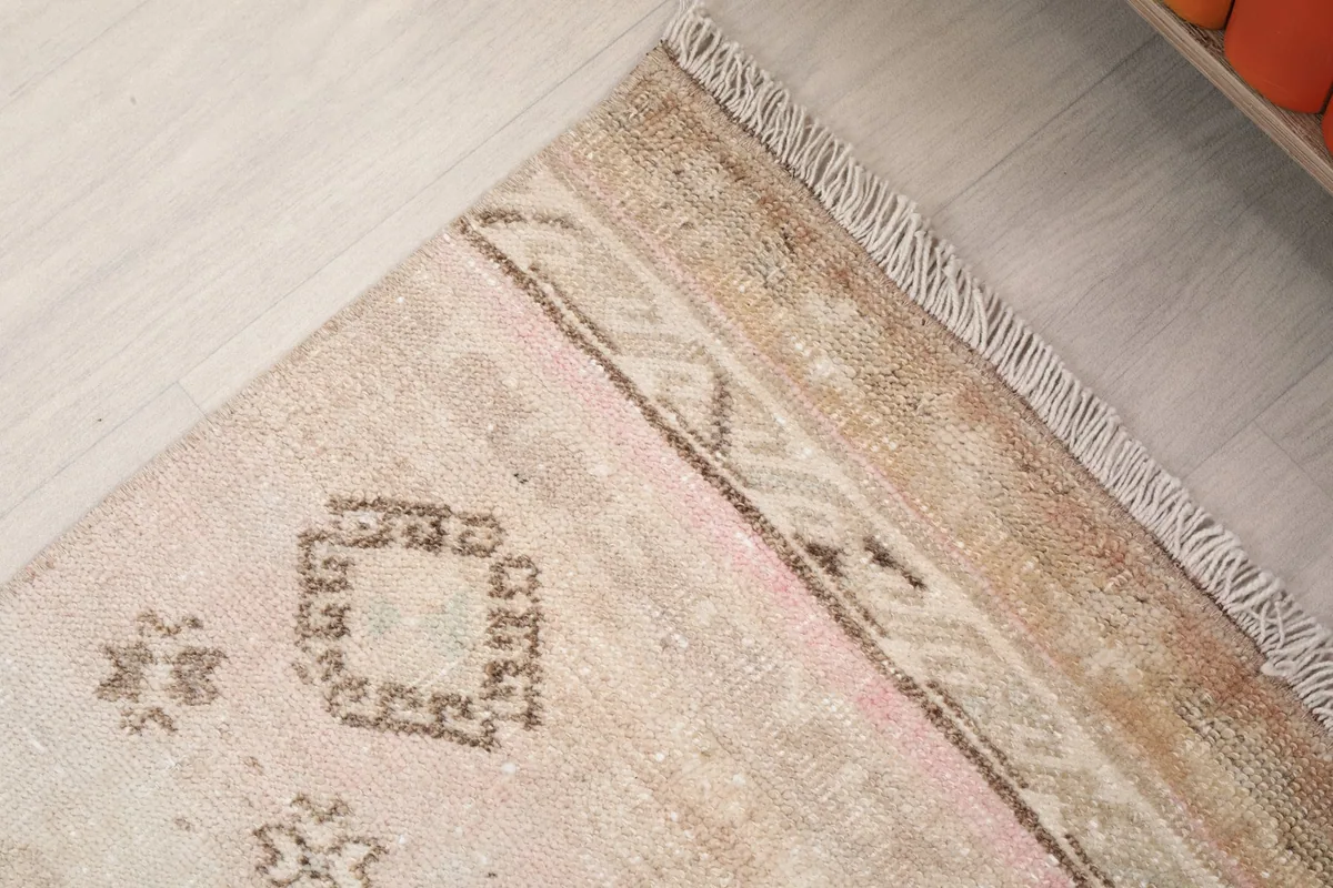 Detailed view of the rug's border and fringe, showing the vintage wear and color