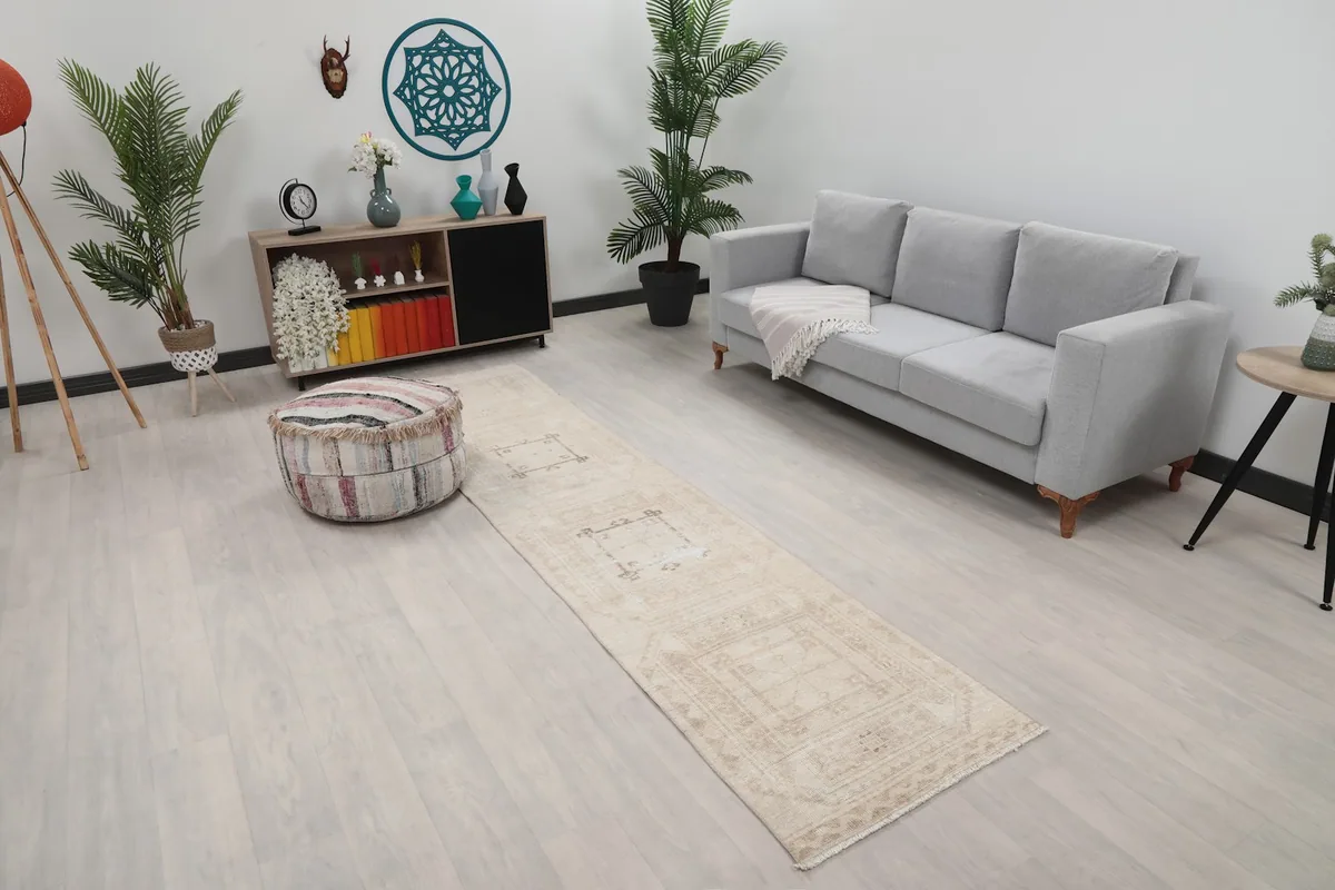 Overhead view of the beige runner rug in a room, showing its length next to a sofa and ottoman.
