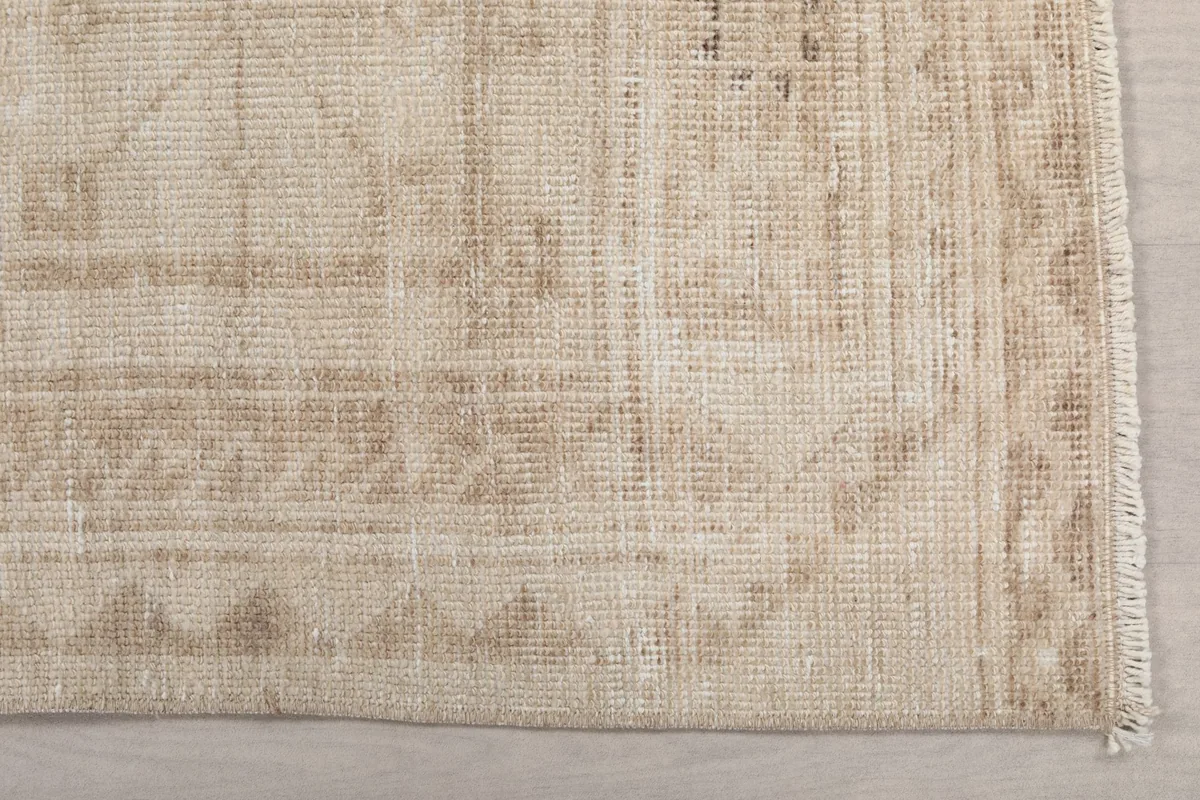 Detailed view of the subtle tan and brown geometric patterns and border on the vintage runner rug.