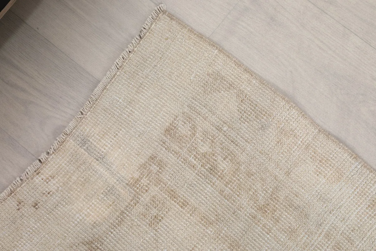 Close-up of the border and edge of the beige runner rug, showing its hand-knotted construction.