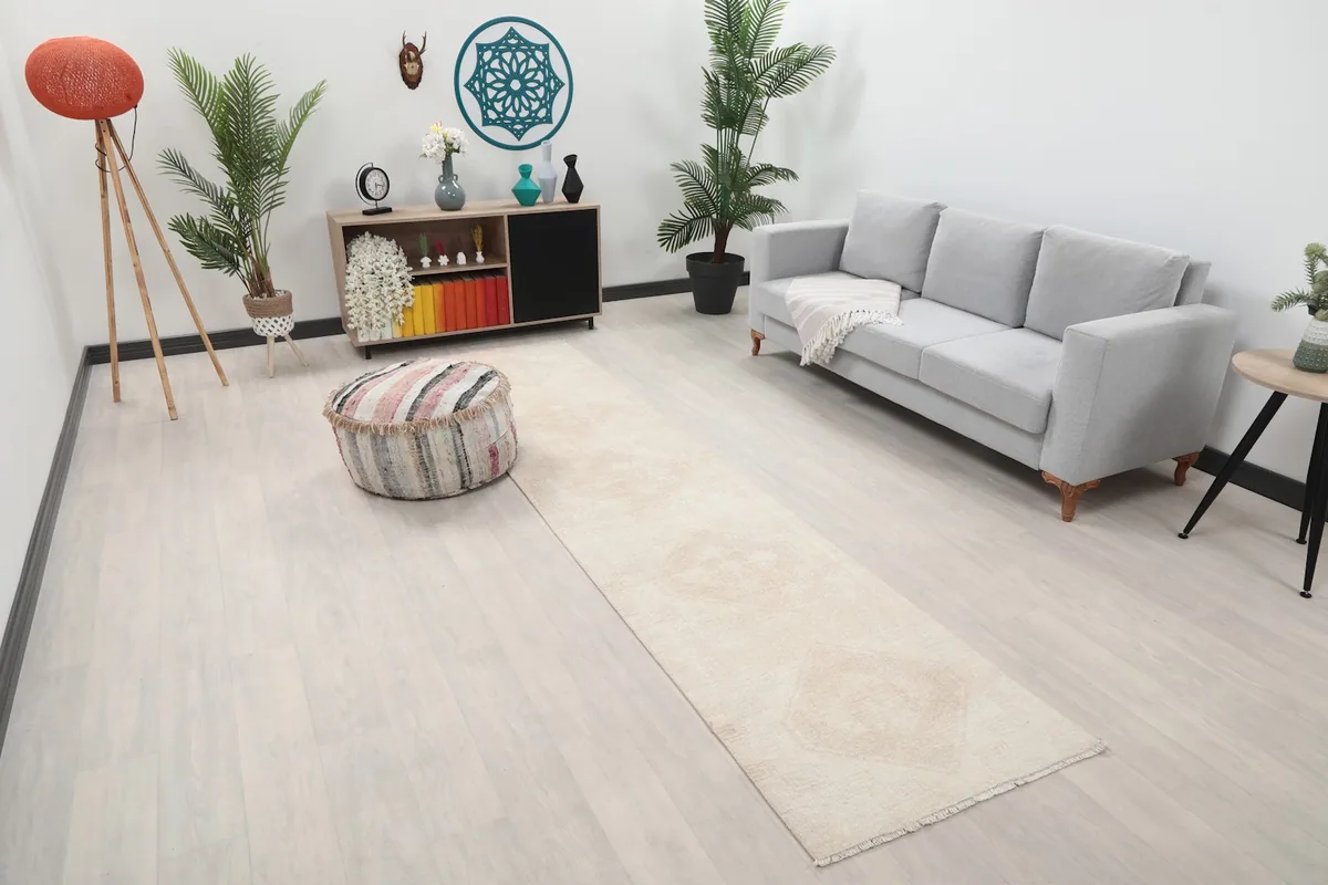 Angle view of the ivory runner rug in a room, showing its length and subtle geometric pattern