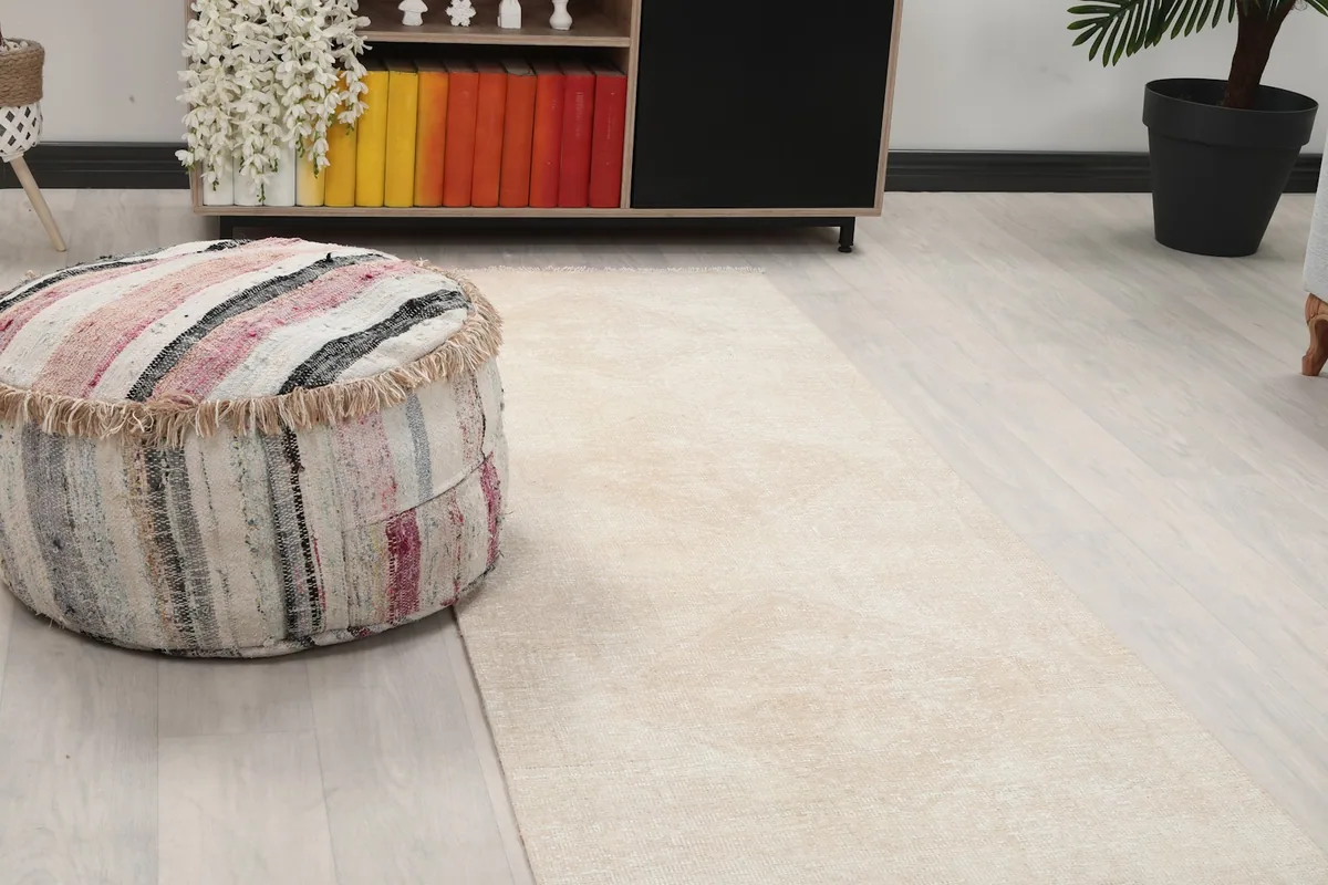 Close-up of the runner rug's faded tan geometric motif next to a striped ottoman