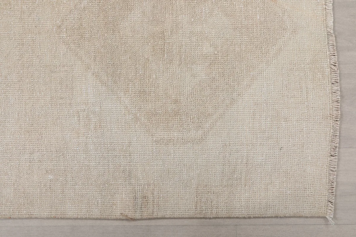 Detailed view of the low wool pile and the subtle, distressed geometric pattern on the rug's surface