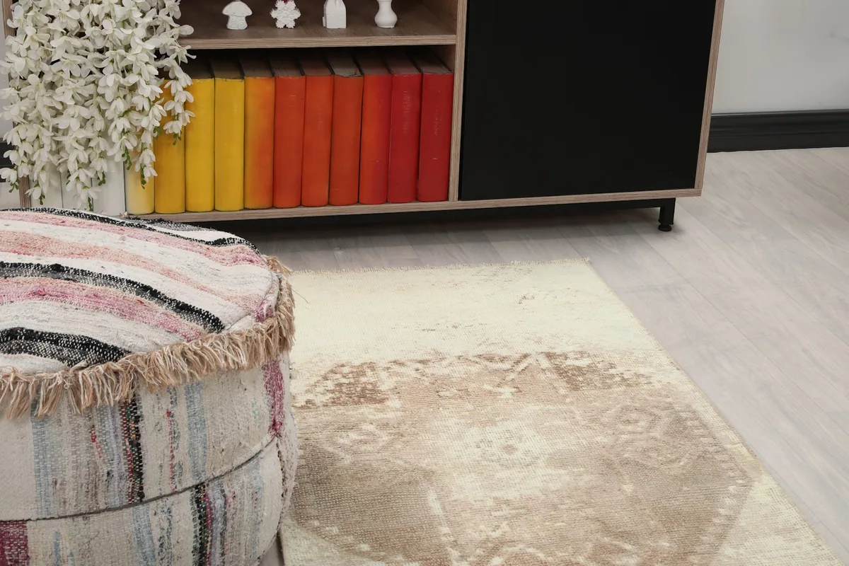 Close-up of the rug's distressed geometric pattern and texture near a decorative pouf
