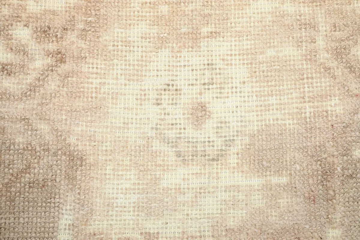 Close-up of the hand-knotted wool pile and faded patterns, revealing the cotton foundation