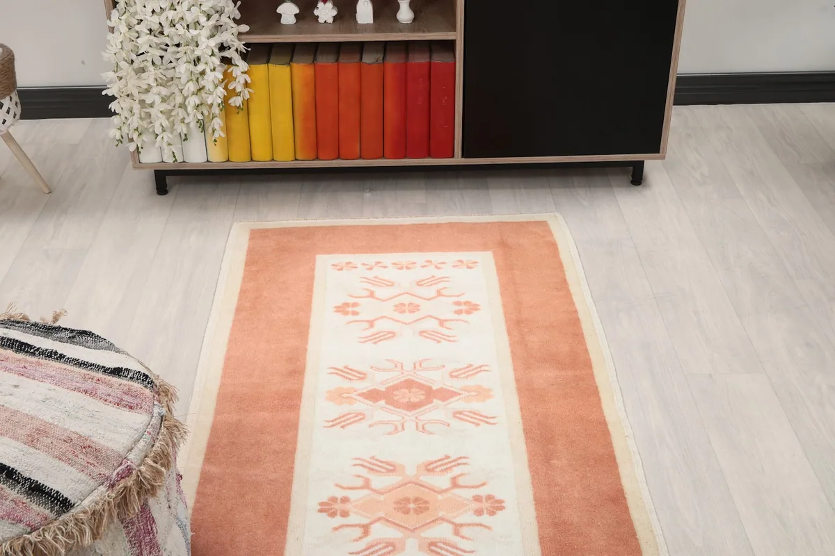Overhead view of the orange and ivory runner rug from one end, showing the full pattern repeat.