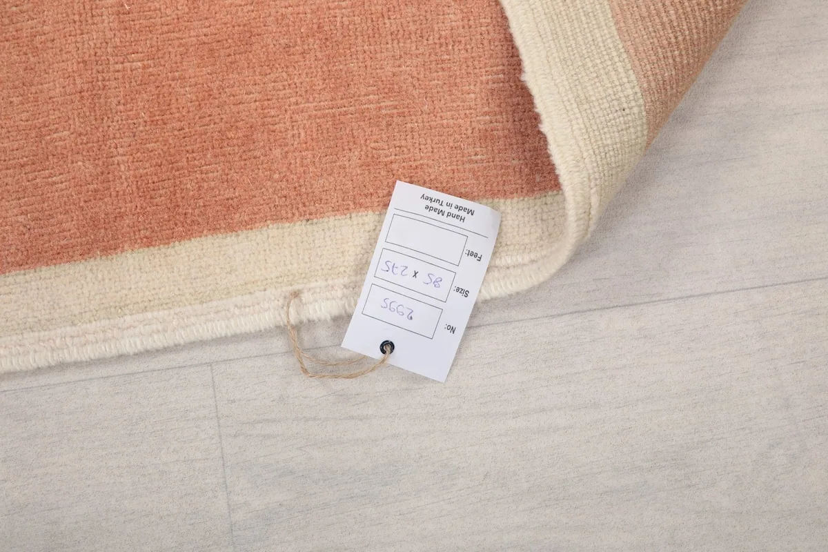 Close-up of the rug's label, indicating its origin and material, attached to the corner.