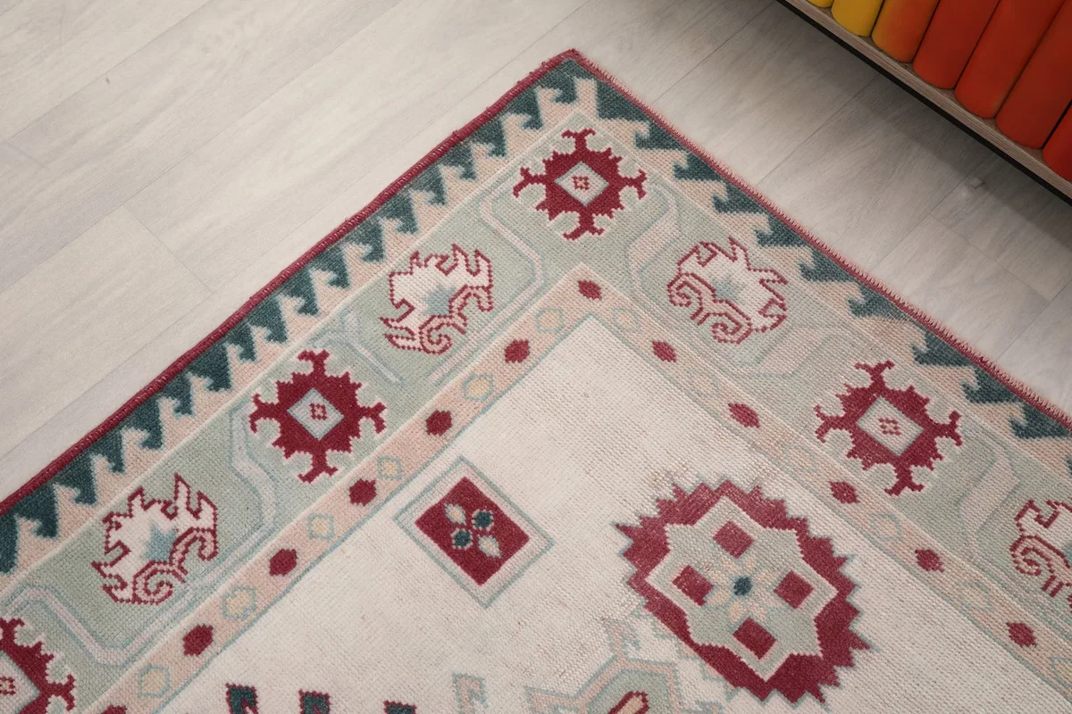 Close-up of a corner of the rug, showing the outer red edge and green border design