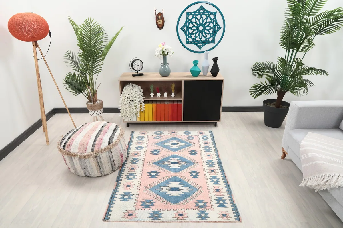 Vintage pink and blue rug styled in a modern living room setting with plants and furniture.