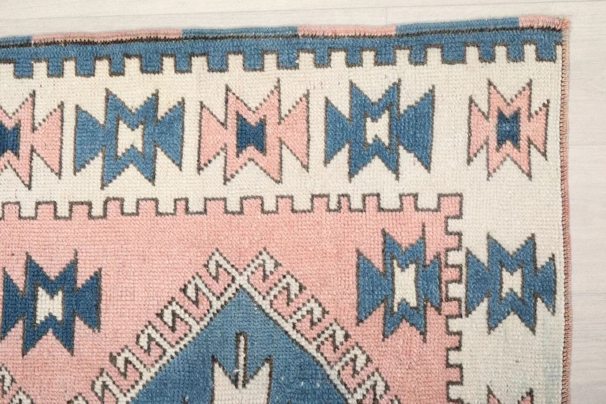 Detailed view of the upper left corner of the rug, highlighting the ivory border and tribal motifs.