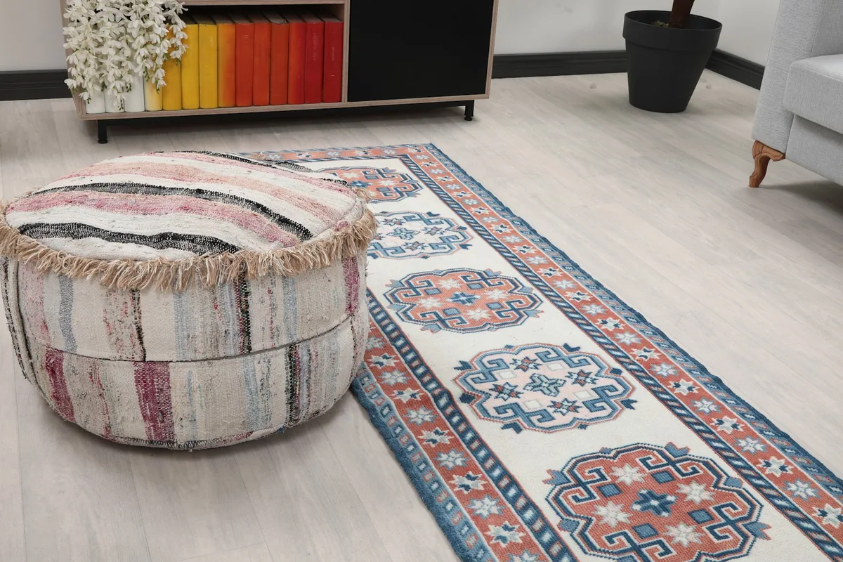 Close-up of the runner rug next to a striped pouf, highlighting a section of the pattern