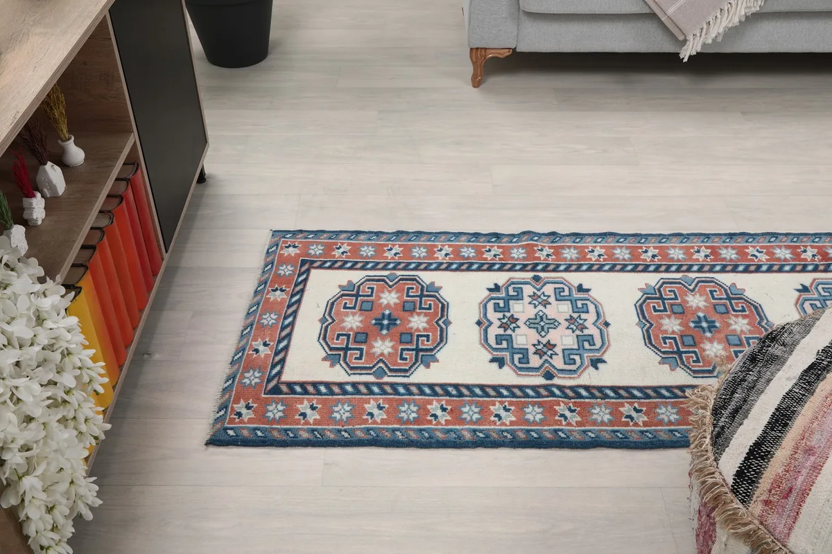 Side view of the runner rug in a room, extending from a cabinet towards a seating area