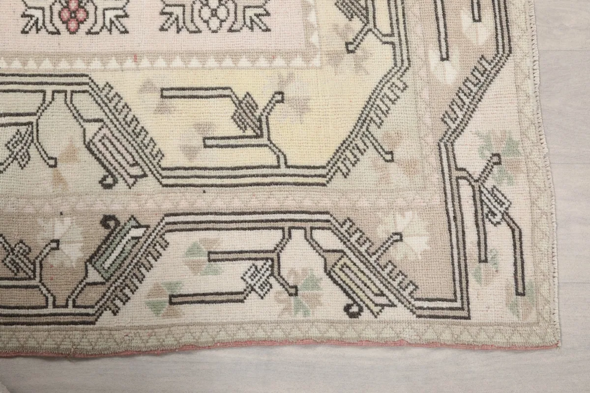 Detailed corner of the rug, highlighting the geometric patterns in ivory, beige, and gray.