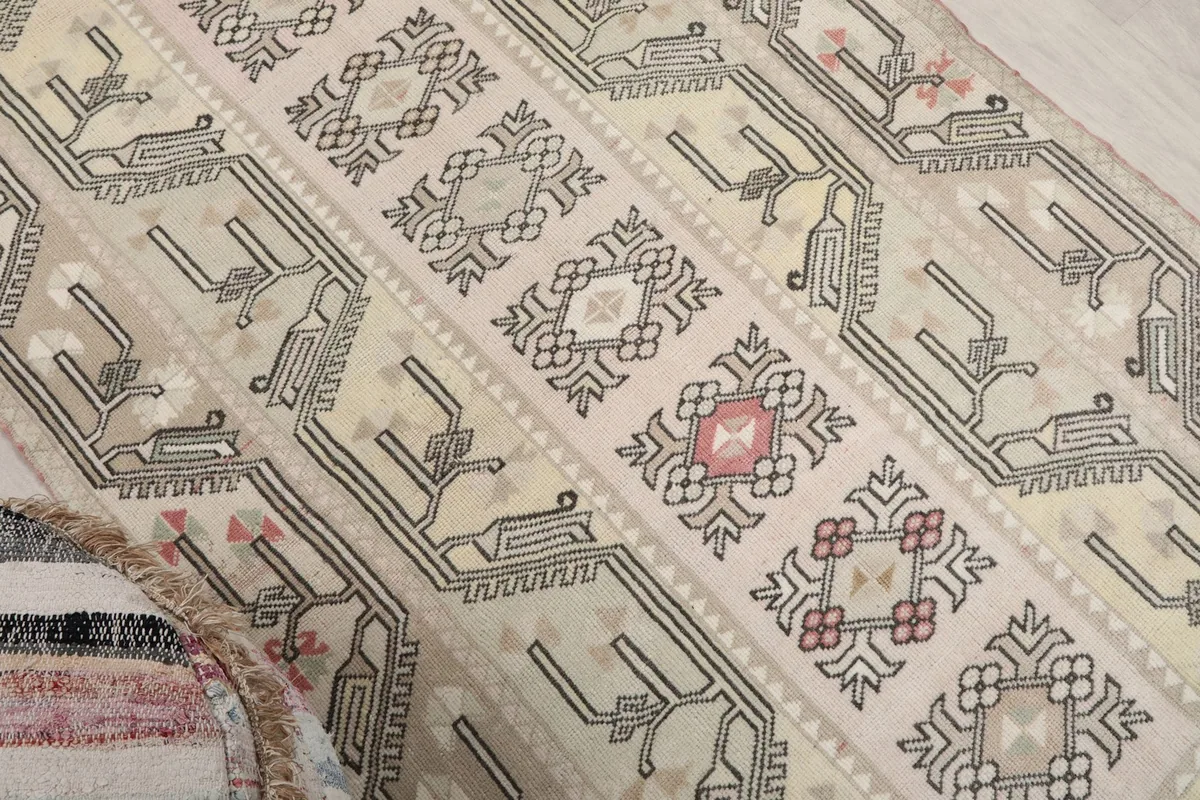 Close-up of the central medallion and tribal motifs in rose, ivory, and gray.