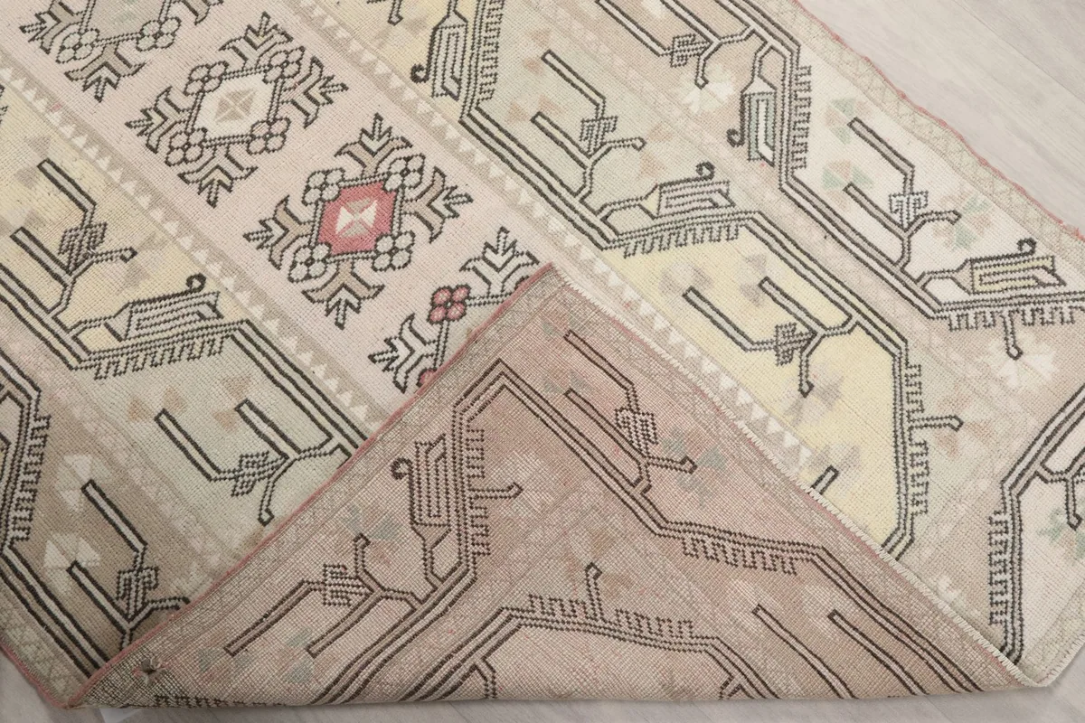 Corner of the rug folded back, revealing the hand-knotted cotton foundation.