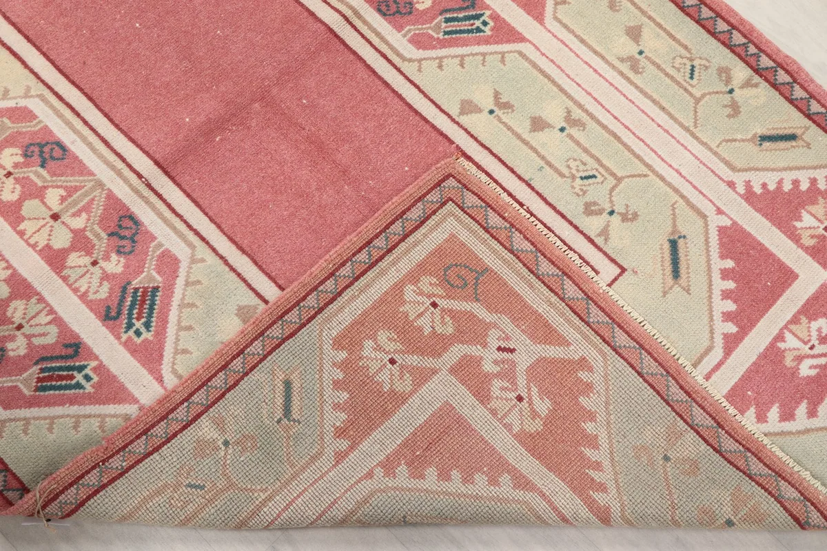 Folded corner of the rug, revealing the back of the hand-knotted wool on cotton foundation.