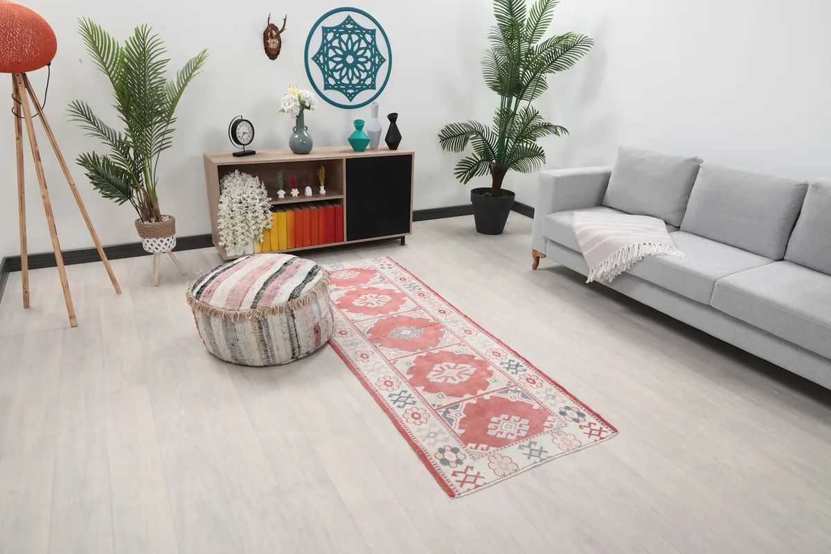 Angled view of the vintage Anatolian runner in a living space, showing its length and colors next to furniture.