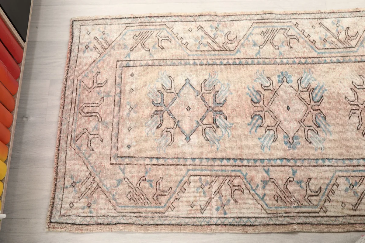 Angled view of the rug's surface, showing the faded colors and design elements