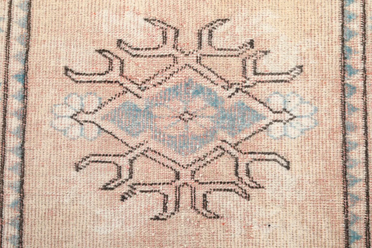 Detailed shot of a single tribal medallion motif in blue and rose beige