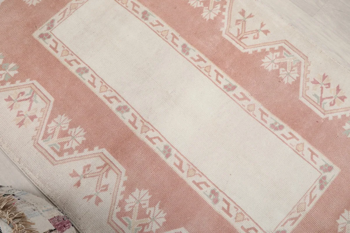 Overhead angled shot of the rug, focusing on the central ivory panel and the surrounding rose border motifs.